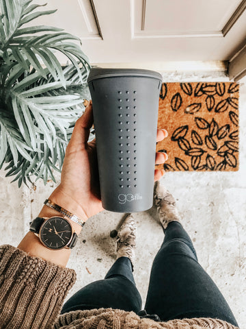 A girl with a stylish outfit holding a grey silicone cup. 