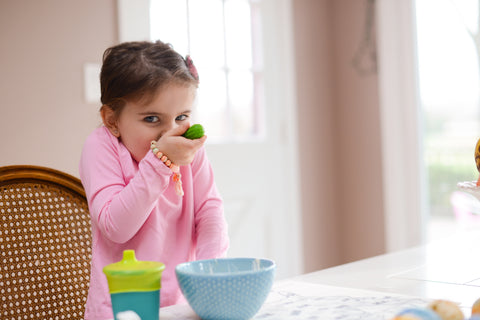 Girl self-feeding unsing a baby silicone spoon