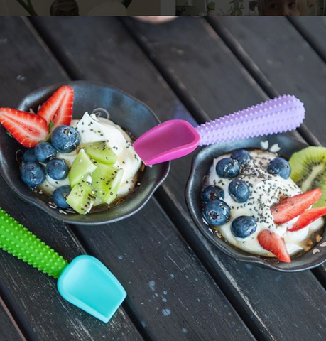 Two bowls of yogurt with fruit and two baby silicone spoons in them